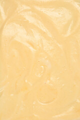 A vertical close-up fills the frame with smooth, light yellow sponge cake batter, showing subtle ripples and air bubbles