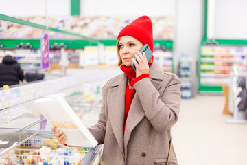 A beautiful middle-aged Caucasian woman is shopping in a supermarket.