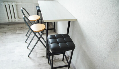 A compact table with stylish black upholstered chairs and stools in the kitchen, interior