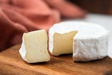 Camembert cheese served with almonds and aged gouda cheese on wooden serving board