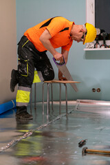 A man is laying wooden flooring. A finishing worker at work. Apartment renovation.