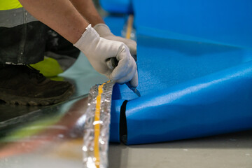 A finishing worker applies an insulating underlayment with an aluminum layer under wooden floor panels. Sound and thermal insulation. Apartment renovation.