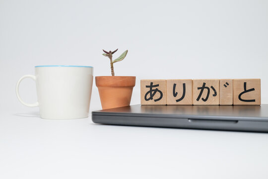 Wooden Blocks with Arigato and Laptop on White Background