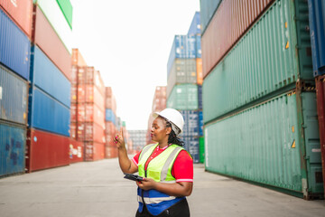 A confident warehouse supervisor in a hard hat uses a tablet and gestures toward digital data, symbolizing smart logistics, cargo tracking, and real-time supply chain technology at a shipping yard.