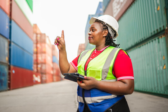A logistics technician in a safety vest uses a tablet and points as though interacting with a holographic interface, representing modern transportation management and technology integration.