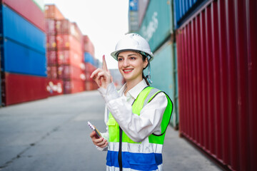A white female logistics worker stands between shipping containers, using digital technology interacts with invisible touchscreen. Show smart logistics, cargo tracking, and modern supply chain.