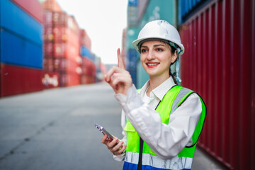 A white woman in construction gear uses virtual touch gestures to control logistics data. The photo conveys smart warehouse management, inventory tracking, and digital in shipping operations.
