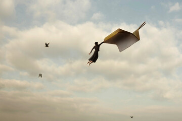 Surrealist concept of freedom, education, and fantasy with a woman suspended from a flying book