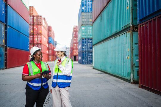 Logistics team members communicate shipment status, using digital tools to track packages and confirm operational tasks in a professional cargo container environment.