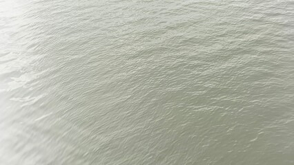 Monsoon season dark sky rain clouds weather reflection on flowing fresh river water surface with wavy and rippling effect. Peaceful aerial top view.