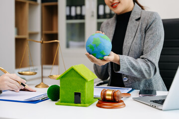 A lawyer presenting a green house model and earth globe with a gavel showing environmental law eco...