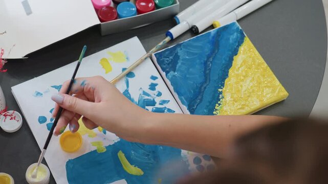 artistic workspace scene, painter reaching for colorful tools, vivid studio with brushes and paints arranged, dynamic art environment with hands mixing bright pigments on vibrant canvas