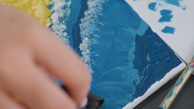 blue brushwork activity, painting with textured blue strokes, applying sponge to create shadow effects, concentrated artist presses sponge into deep blue to craft wave shadows vividly