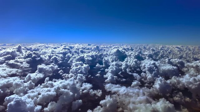 Cockpit view in a peacul flight in the upper atmosphere over cottyny cumulus clouds under a deep blue sky.
