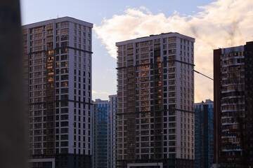 Fototapeta premium City view on a sunny day. Modern building and houses against the blue sky.