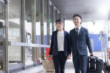 Fototapeta premium ビジネス出張でスーツケースを引く会社員の笑顔の移動シーン