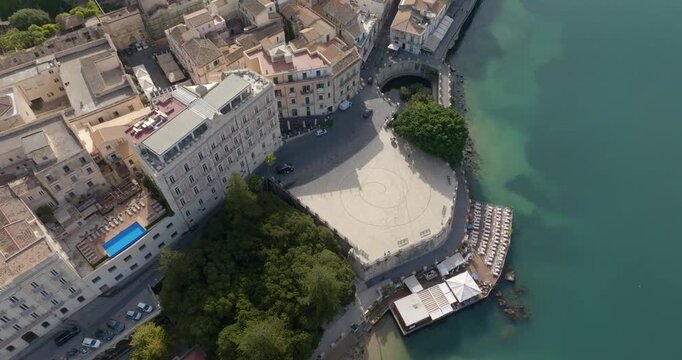 Aerial closeup of the Fountain of Arethusa. It's a natural spring on the island of Ortygia in the historic center of the city of Syracuse, Sicily, Italy. There's a square overlooking the turquoise sea