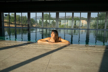 Woman relaxing in indoor pool with scenic mountain view