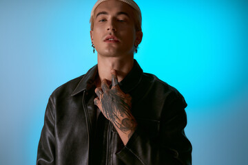 Fototapeta premium A stylish young man shows off his tattoos and trendy outfit, exuding modern confidence.