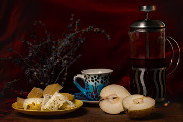 A composition of pears and pieces of delicious cheese with an oriental cup and teapot, decorated with sprigs of lavender.