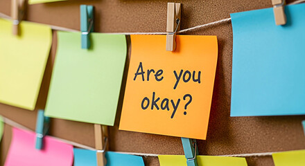 Colorful sticky notes with the question "Are you okay?" displayed on a corkboard creating a supportive and caring atmosphere for mental health awareness and emotional wellbeing