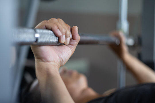 Close-up of a man’s hand gripping a barbell during bench press workout in the gym, control focused muscle training in a fitness lifestyle.