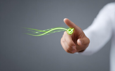 Finger touching virtual green check mark icon displays approval and successful completion of task with confident gesture against grey background
