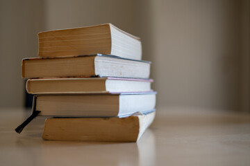 Stack of old books on a wooden table in natural light, creating a calm and vintage study atmosphere. Perfect for education, literature library-related editorial and commercial use.