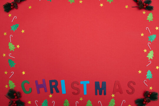 Red background featuring christmas letters, glitter trees, candy canes and stars creating a festive frame