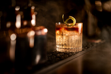A cocktail being mixed and carefully finished in a bar, presented under warm candlelight.