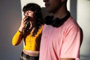 Latina woman savoring fruit near Latino man reflecting urban shared moment