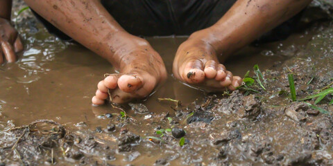 Close up of a child's feet playing in a muddy puddle