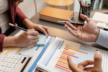 Business professionals meeting at a modern office table, reviewing charts and budget reports while discussing key financial insights and strategic plans for upcoming business decisions.