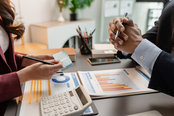 Business professionals meeting at a modern office table, reviewing charts and budget reports while discussing key financial insights and strategic plans for upcoming business decisions.