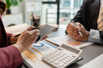 Business professionals meeting at a modern office table, reviewing charts and budget reports while discussing key financial insights and strategic plans for upcoming business decisions.