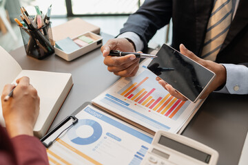 Business professionals meeting at a modern office table, reviewing charts and budget reports while discussing key financial insights and strategic plans for upcoming business decisions.