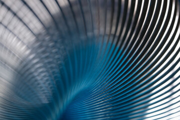 Abstract industrial metal background with curved steel lines on blue. Macro view of shiny metallic spiral spring texture for hardware manufacturing presentation. Photo