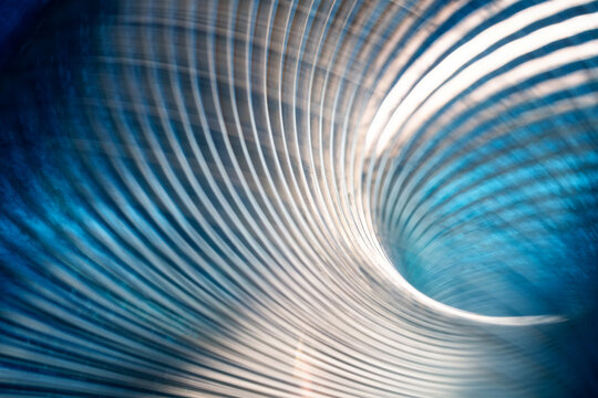 Abstract industrial metal background with curved steel lines on blue. Macro view of shiny metallic spiral spring texture for hardware manufacturing presentation. Photo