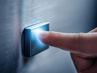 Finger pressing a modern illuminated metallic button on a textured wall, symbolizing technology interaction and futuristic control concepts