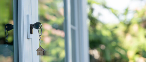 Landlord key for unlocking house is plugged into the door. Second hand house for rent and sale. keychain is blowing in the wind. mortgage for new home, buy, sell, renovate, investment, owner, estate