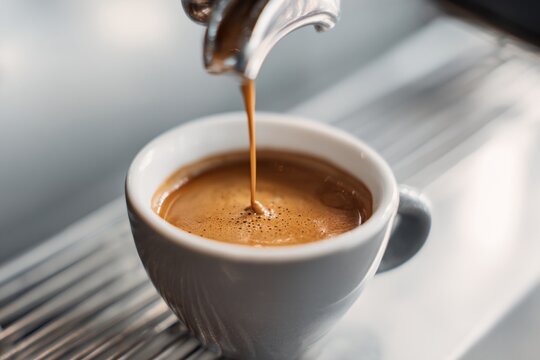 Cup of coffee is being poured into a white cup
