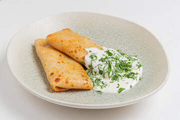 Savory crepes stuffed with flavorful fillings, served alongside a creamy herb sauce