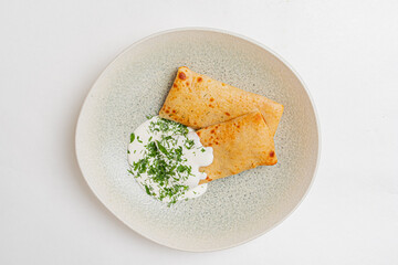Crispy pancakes are beautifully arranged on a plate, accompanied by fresh herb yogurt for dipping