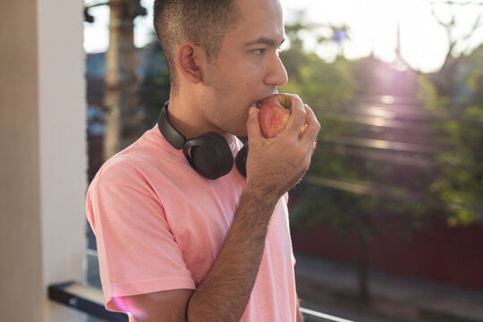 Casual guy taking a bite of his apple in warm sunlight