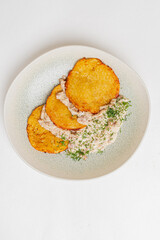 Fried plantain slices are perfectly arranged beside a savory tuna salad topped with herbs