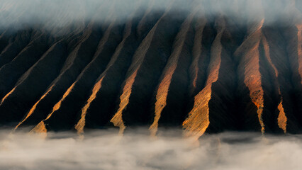 Volcanic mountain with a sinuous silhouette bathed in the sun at dawn