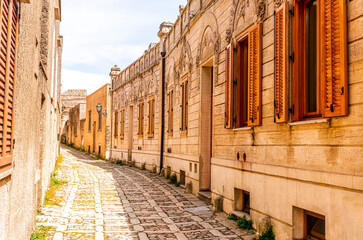 old narrow italian street in traditional mediterranean style with yellow stone walls and beautiful windows. Amazing antuque buildings on a old inalian street.