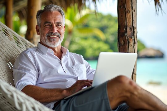 A Mature Man Relaxing on a Hammock in a Tropical Paradise with a Laptop