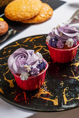 Two beautifully crafted cupcakes with vibrant purple frosting rest on a stylish black plate