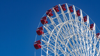 A large Ferris wheel, entirely painted red, is captured from the side, showcasing its circular...